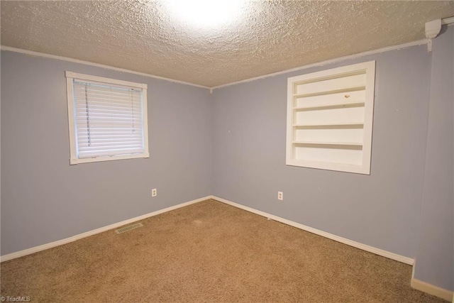 carpeted spare room featuring visible vents, a textured ceiling, crown molding, and built in shelves