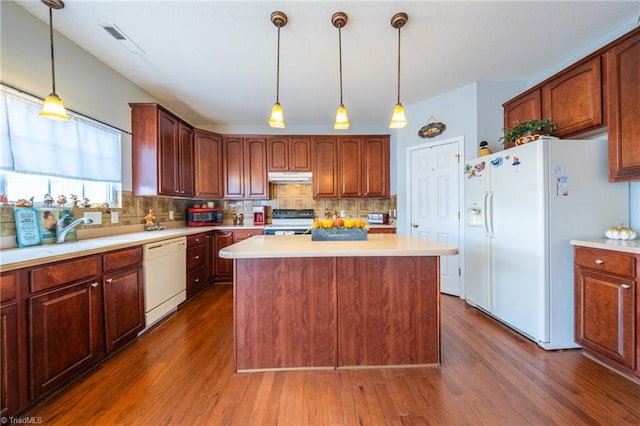 kitchen with decorative backsplash, dark hardwood / wood-style flooring, white appliances, decorative light fixtures, and a center island