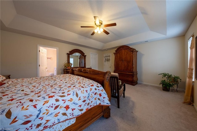 carpeted bedroom with ceiling fan, connected bathroom, and a tray ceiling