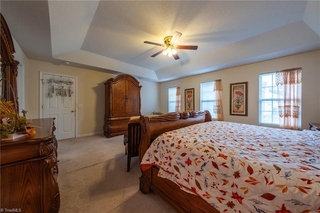 bedroom featuring ceiling fan, a raised ceiling, and light carpet