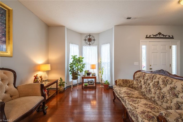 living area with dark wood-type flooring and a textured ceiling