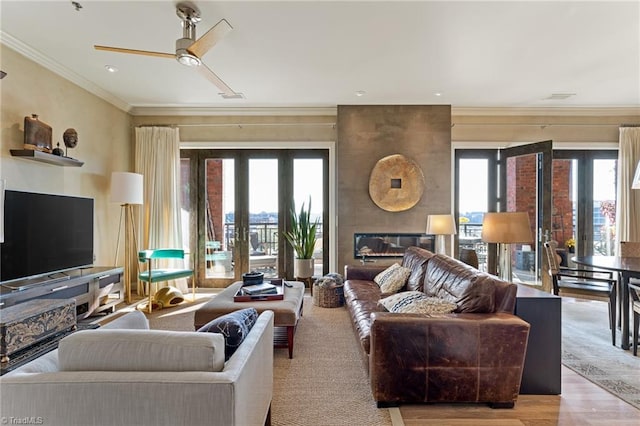 living room featuring ornamental molding, ceiling fan, light hardwood / wood-style floors, and a healthy amount of sunlight