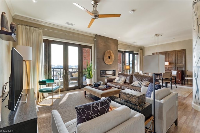 living room with a healthy amount of sunlight, light wood-type flooring, french doors, and crown molding