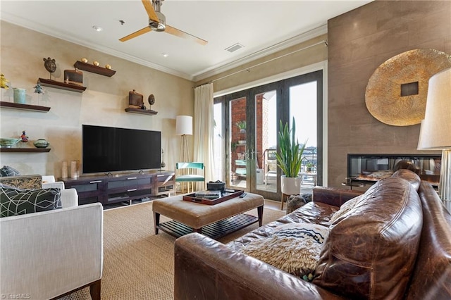 living room featuring ceiling fan, french doors, a large fireplace, and crown molding