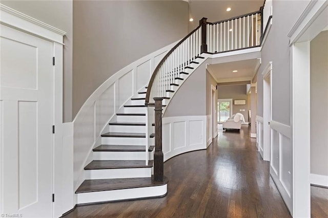 stairs with a towering ceiling, ornamental molding, and wood-type flooring