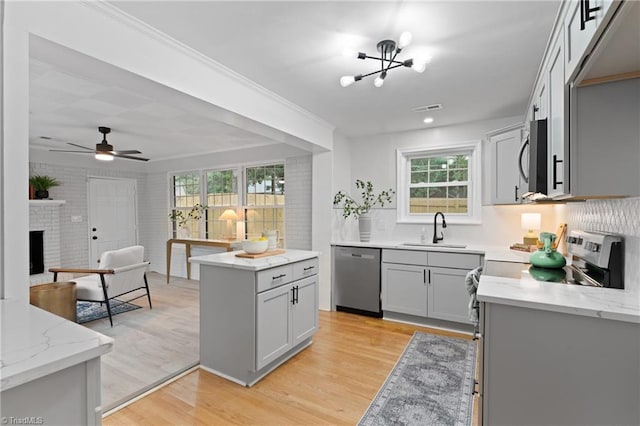 kitchen with light stone counters, a sink, stainless steel appliances, visible vents, and light wood-style floors
