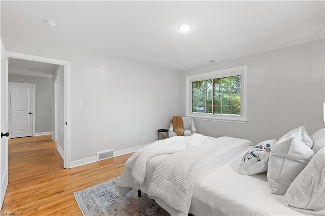 bedroom featuring baseboards, light wood-style floors, and visible vents