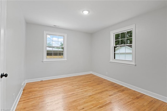 empty room featuring light wood-style flooring, baseboards, and visible vents