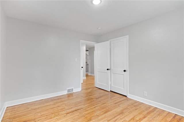 spare room featuring baseboards, visible vents, and light wood-style floors