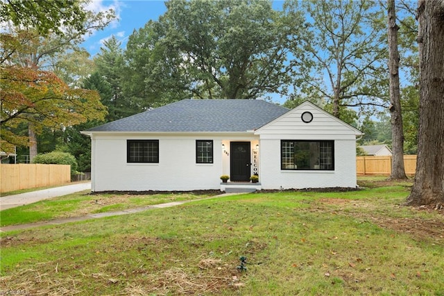view of front of house featuring brick siding, a front yard, and fence