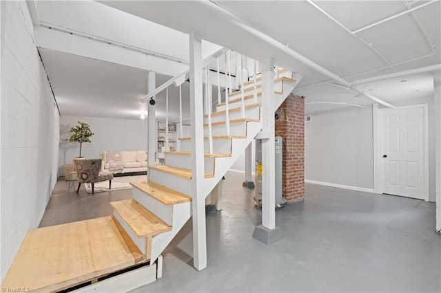 stairs with water heater, concrete floors, and concrete block wall