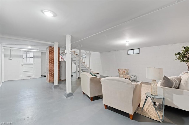 living room with stairs, concrete block wall, and finished concrete floors