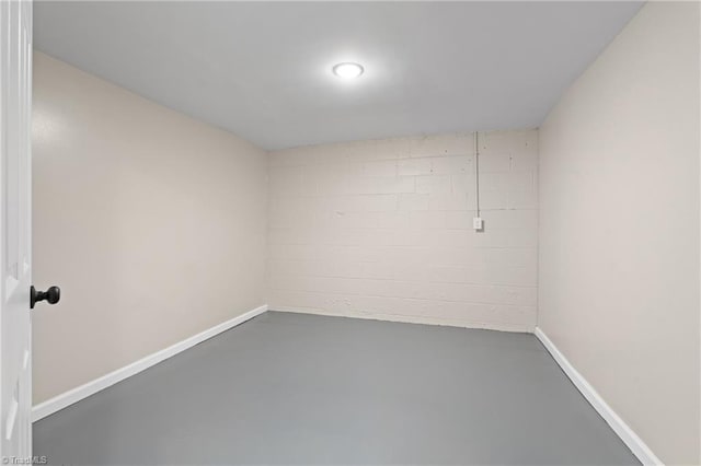 empty room with baseboards, concrete floors, and concrete block wall