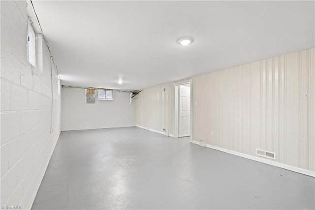 basement with concrete block wall, electric panel, and visible vents