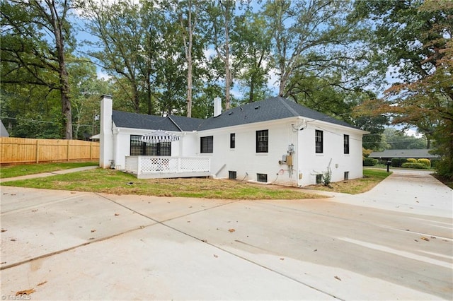 back of house featuring driveway, a chimney, and fence