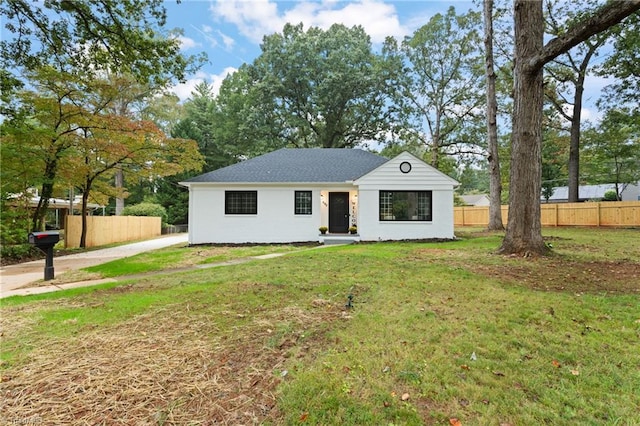 view of front of home with stucco siding, fence, and a front lawn