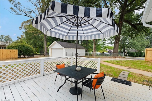 wooden terrace with an outdoor structure, outdoor dining space, fence, and a detached garage