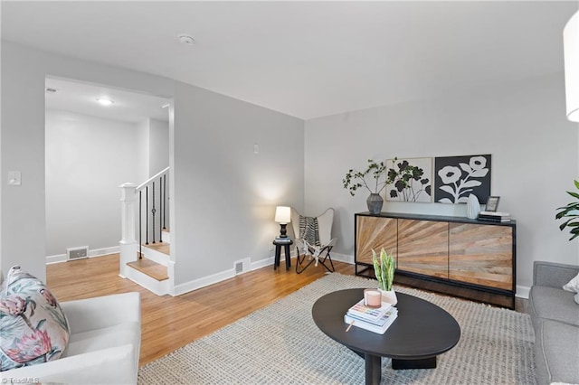 living area with baseboards, visible vents, wood finished floors, and stairway