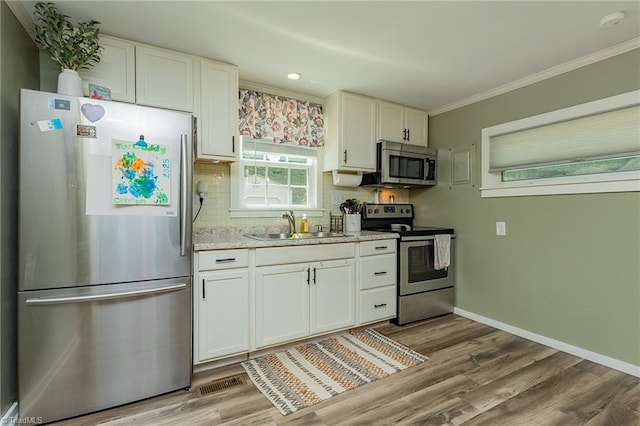 1055 Old Silver Hill Rd, Lexington, NC 27292 - kitchen with appliances with stainless steel finishes, a sink, decorative backsplash, white cabinetry, and crown molding