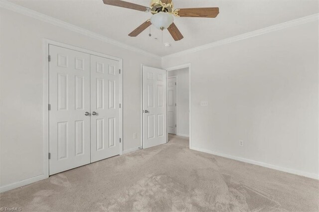 unfurnished bedroom with ceiling fan, crown molding, light carpet, and a closet