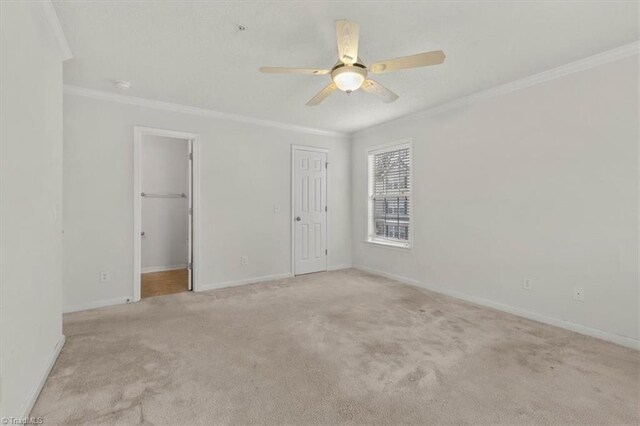 spare room with light carpet, ceiling fan, and crown molding