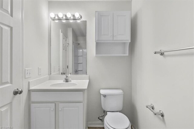 bathroom with walk in shower, vanity, and toilet