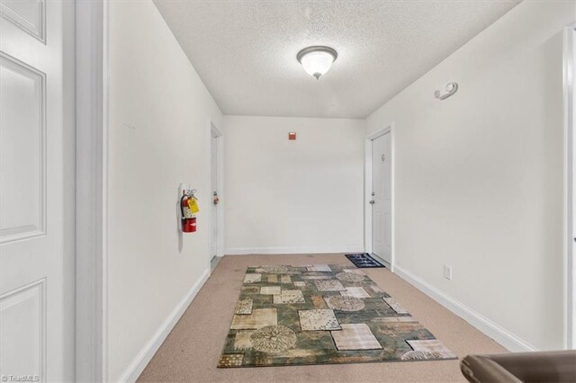 hallway with carpet and a textured ceiling