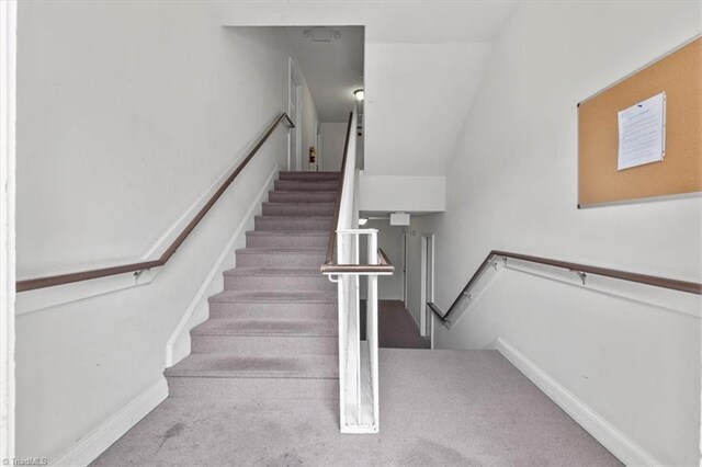 stairway featuring carpet flooring and vaulted ceiling