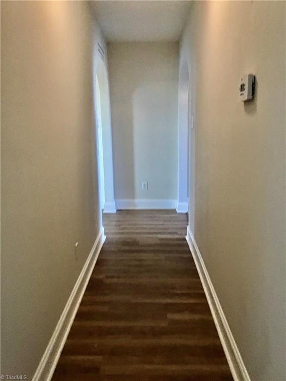 corridor with baseboards and dark wood-style flooring