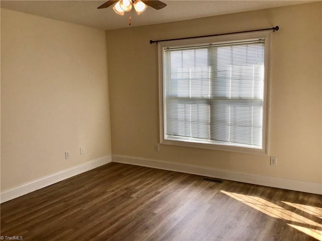 empty room with dark wood-type flooring, visible vents, baseboards, and a ceiling fan