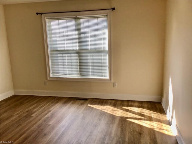 spare room with baseboards and wood finished floors