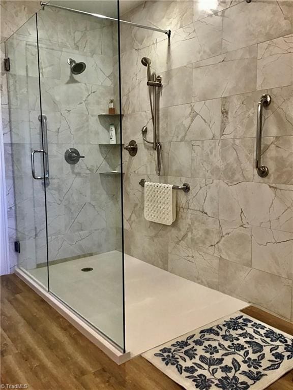 full bath featuring wood finished floors and a shower stall