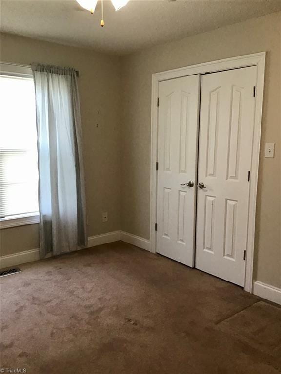 unfurnished bedroom with carpet flooring, a ceiling fan, visible vents, baseboards, and a closet