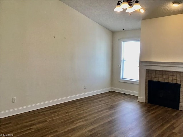 unfurnished living room featuring dark wood-style floors, a textured ceiling, a fireplace, and baseboards