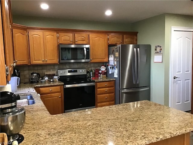 kitchen with appliances with stainless steel finishes, recessed lighting, brown cabinets, and backsplash