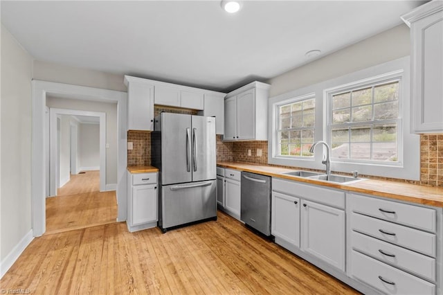 kitchen featuring light wood-type flooring, appliances with stainless steel finishes, white cabinetry, sink, and butcher block counters