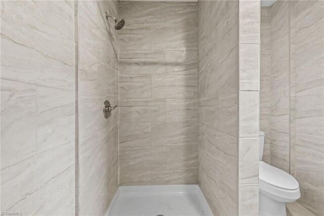 bathroom with tiled shower and toilet