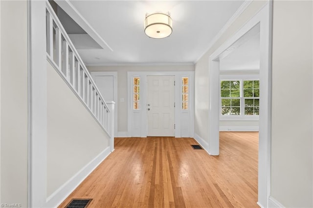 entryway with light hardwood / wood-style floors and crown molding