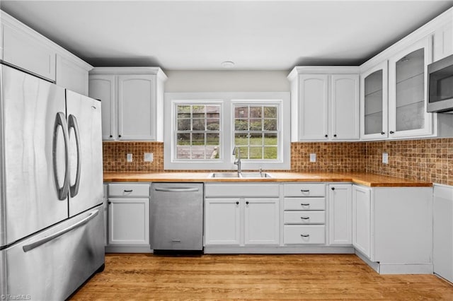 kitchen with white cabinetry, backsplash, sink, appliances with stainless steel finishes, and light hardwood / wood-style floors