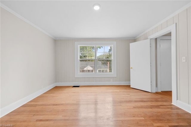 spare room featuring crown molding and light hardwood / wood-style flooring