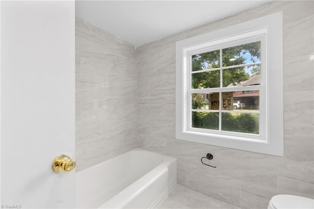 bathroom with tile walls, toilet, and  shower combination