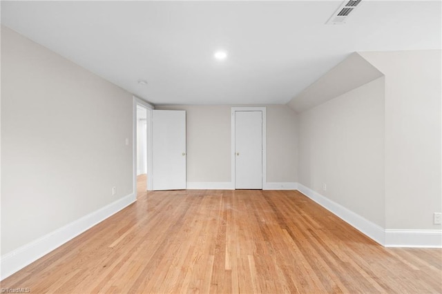 unfurnished bedroom featuring vaulted ceiling and light hardwood / wood-style flooring