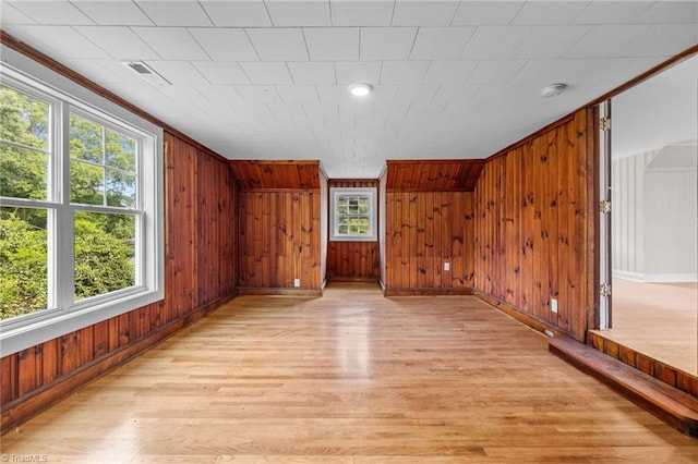 bonus room with a healthy amount of sunlight, light hardwood / wood-style flooring, and wood walls