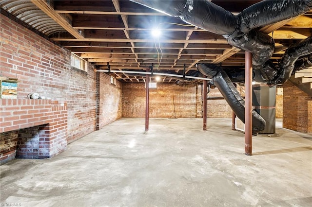 basement featuring brick wall and heating unit