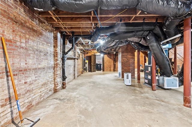 basement with electric water heater and brick wall