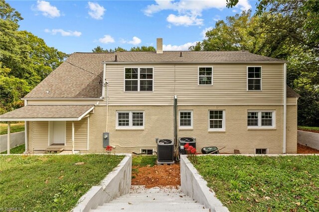 rear view of property featuring a yard and central air condition unit