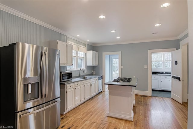 kitchen featuring white cabinets, appliances with stainless steel finishes, light wood-style floors, and a sink