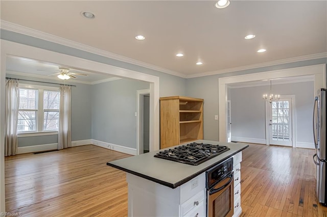 kitchen featuring oven, black gas cooktop, ornamental molding, light wood-style flooring, and freestanding refrigerator