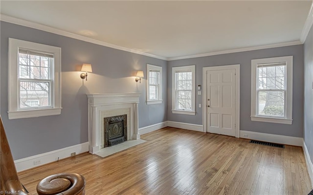 unfurnished living room with a healthy amount of sunlight, crown molding, and wood finished floors