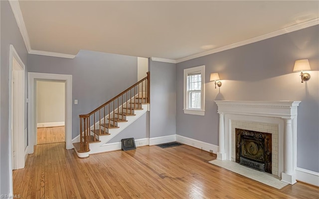 unfurnished living room with stairs, wood finished floors, and baseboards